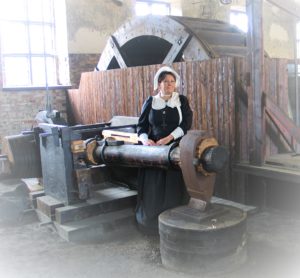 historialliseesn asuun pukeitunut nainen ison vesivasaran vieressä